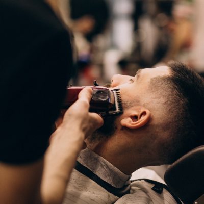 uomo-in-un-salone-di-barbiere-facendo-taglio-di-capelli-e-taglio-della-barba_1303-20954