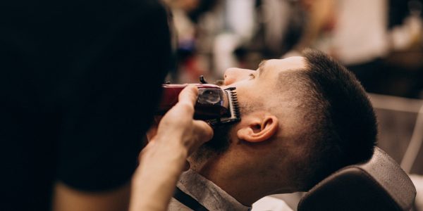 uomo-in-un-salone-di-barbiere-facendo-taglio-di-capelli-e-taglio-della-barba_1303-20954